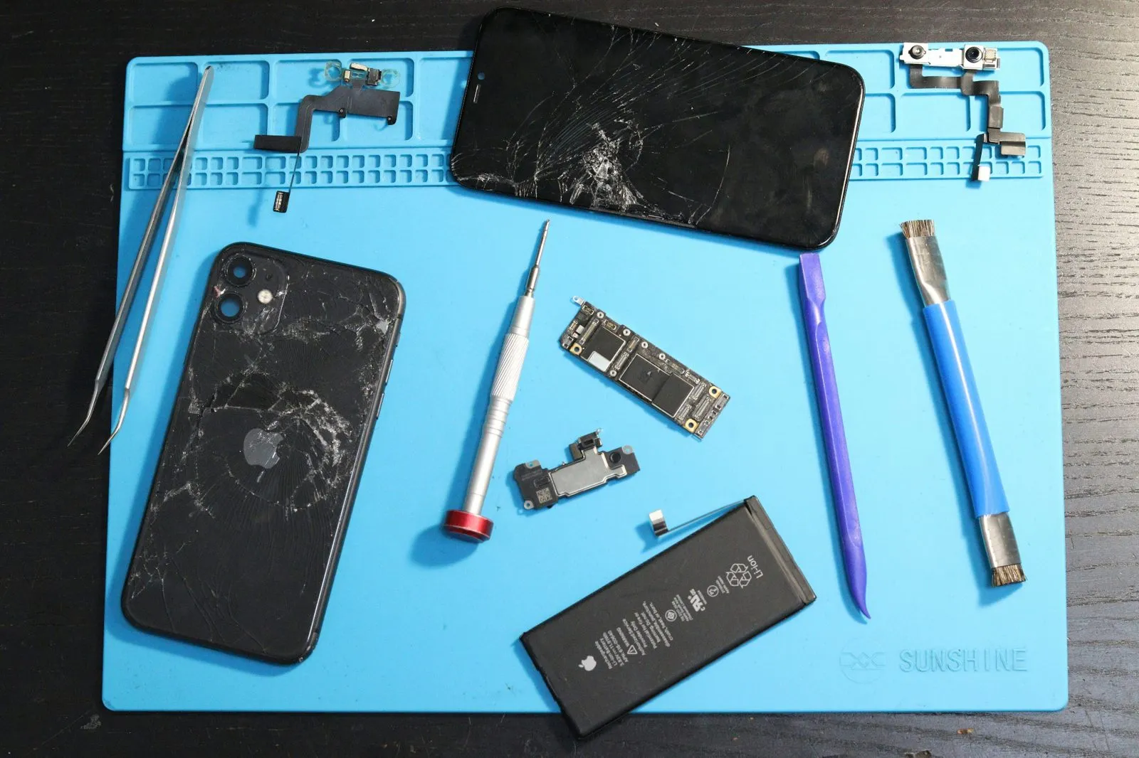 Phone opened on a magnetic repair mat with labeled screws